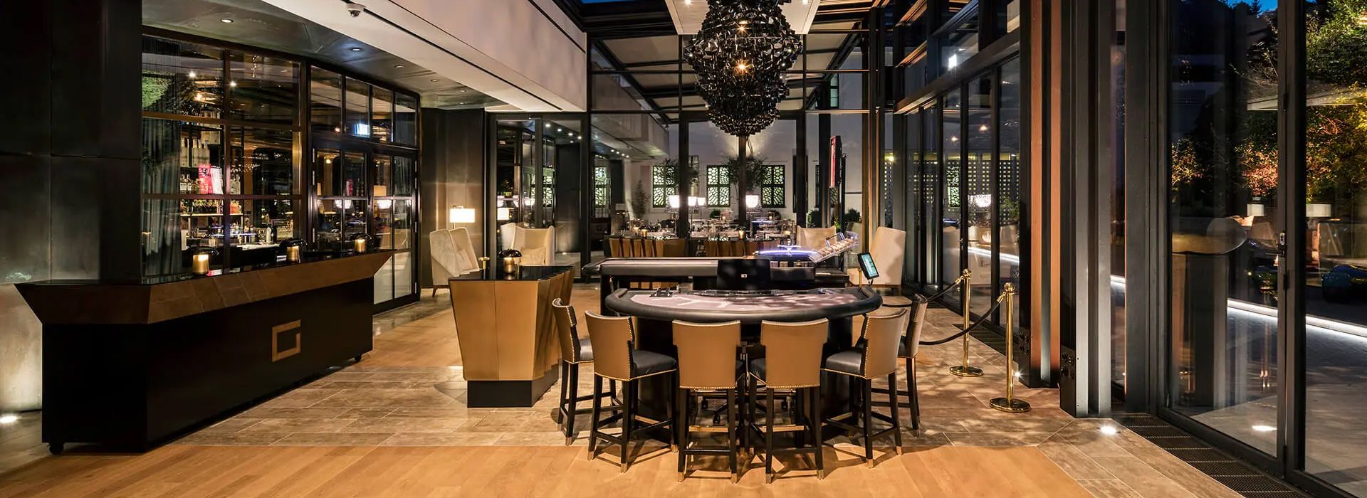 Modern lounge with circular bar, chandelier, high stools, and bright ambiance