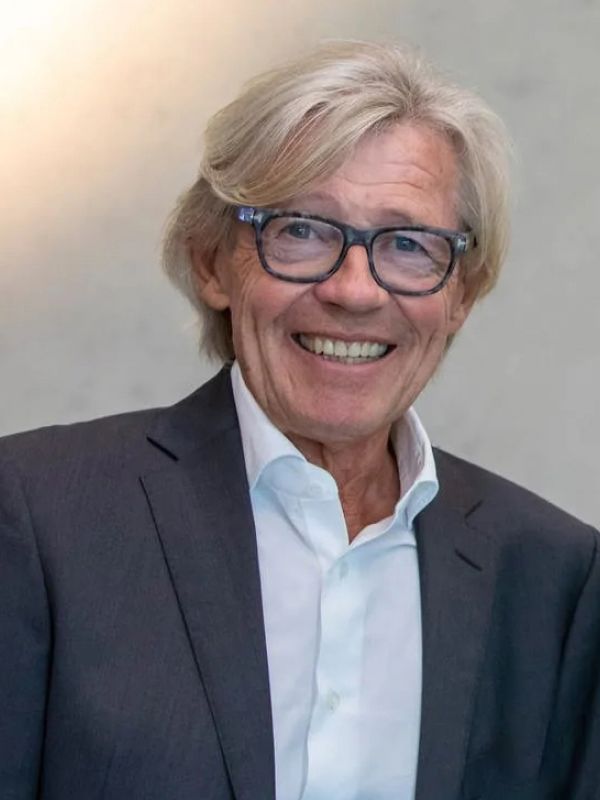 Smiling older man in suit, glasses, light hair, light background