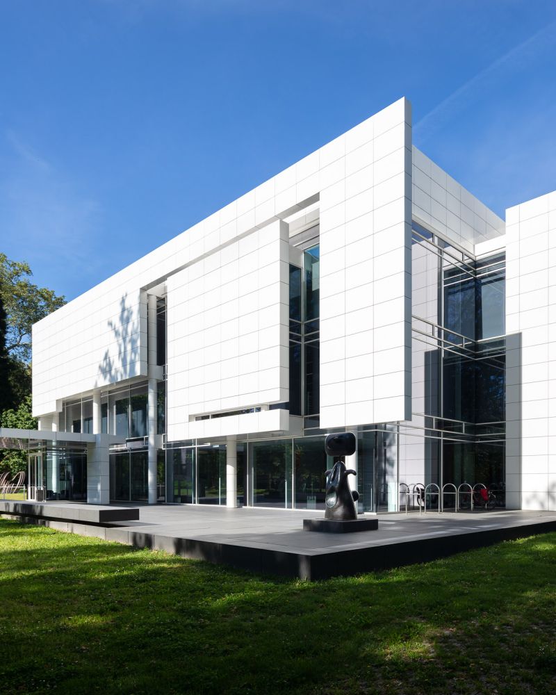 Minimalist white building with glass windows and abstract black sculpture