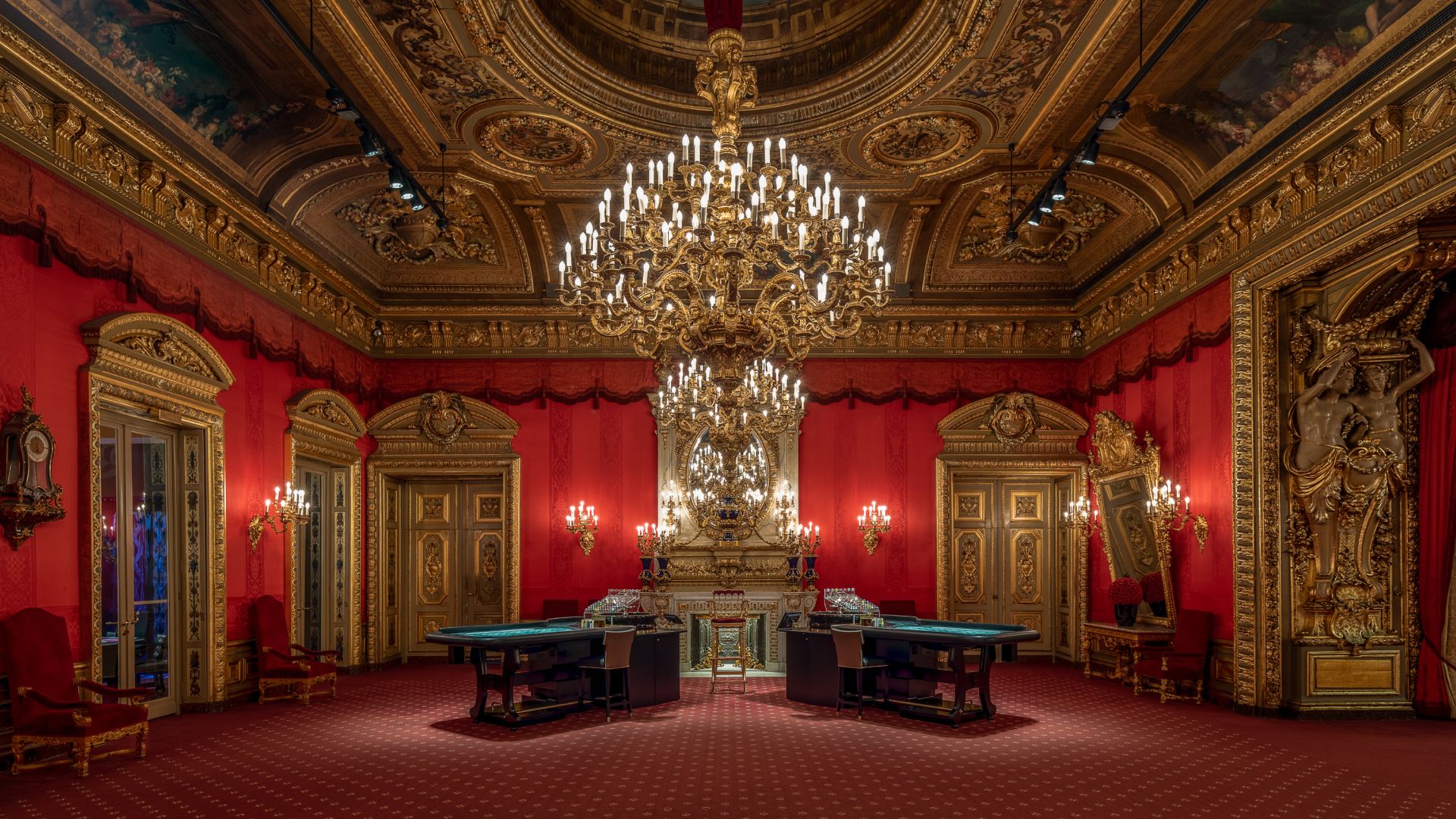 Luxurious room with gold decor, chandelier, red walls, and elegant furnishings.