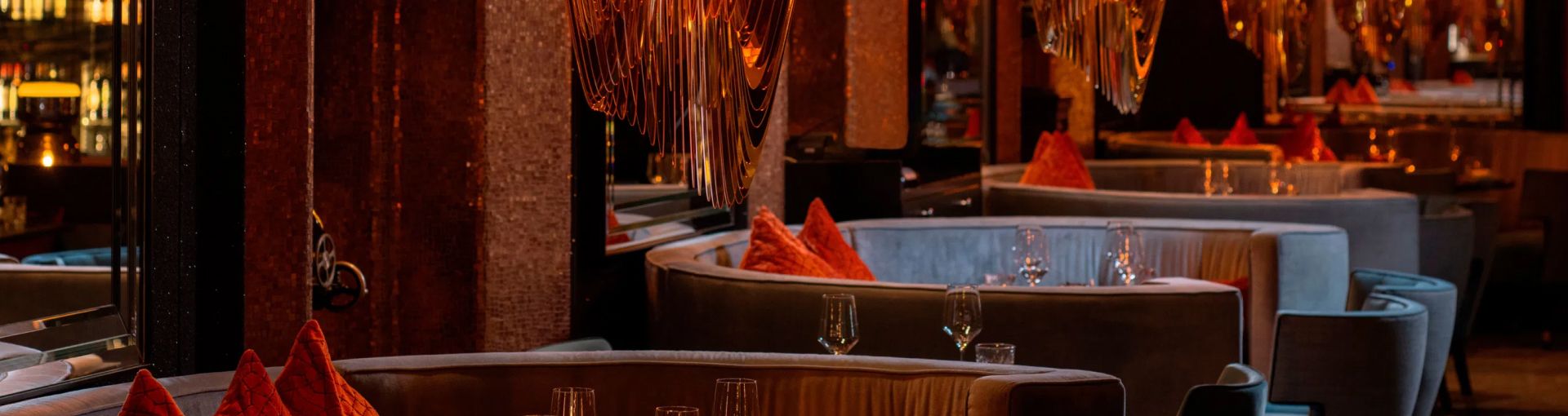 Upscale restaurant with warm lighting and plush seating in semi-circular arrangement