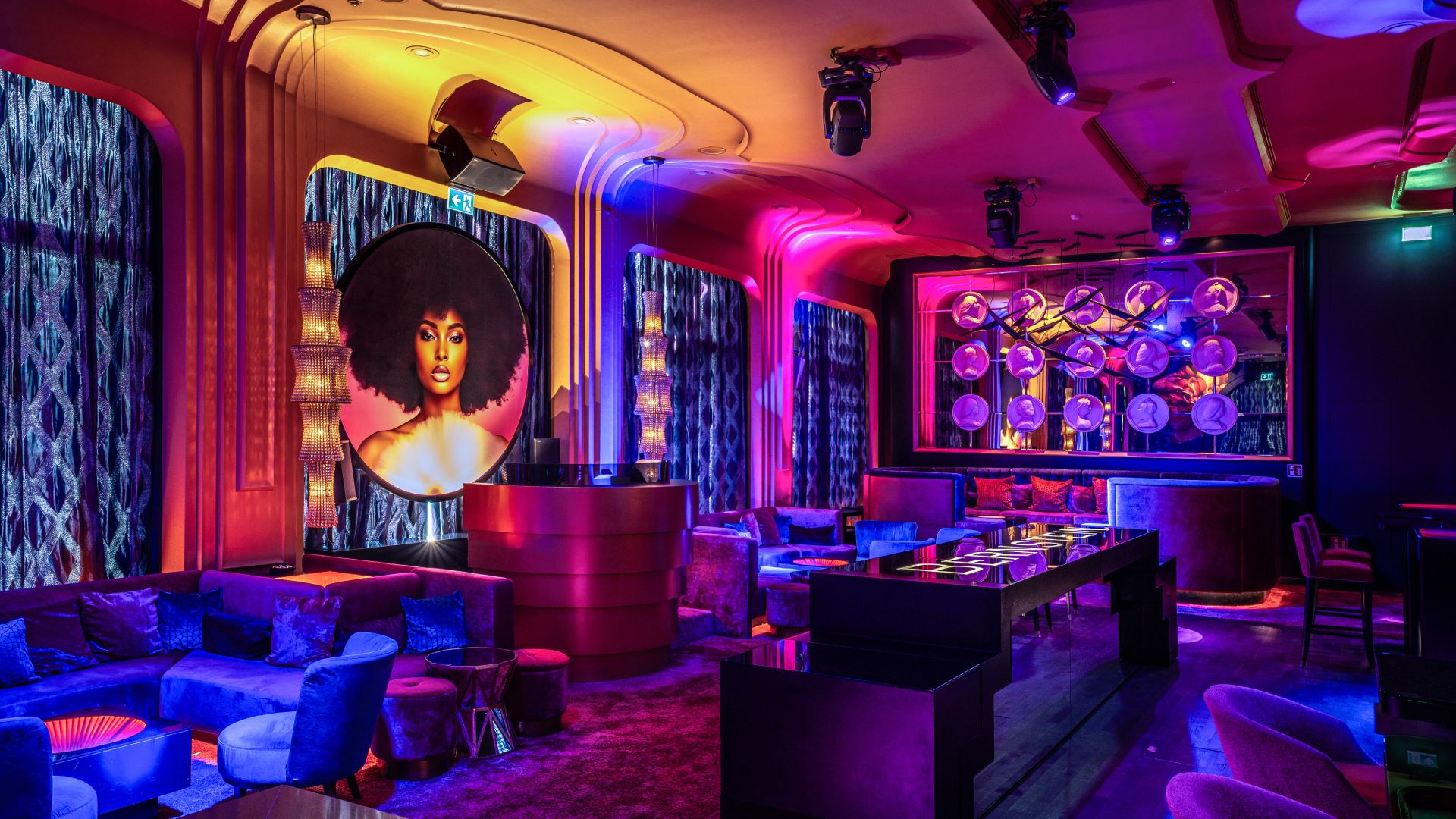 Vibrant nightclub with afro mural, colorful lighting, and modern bar area.