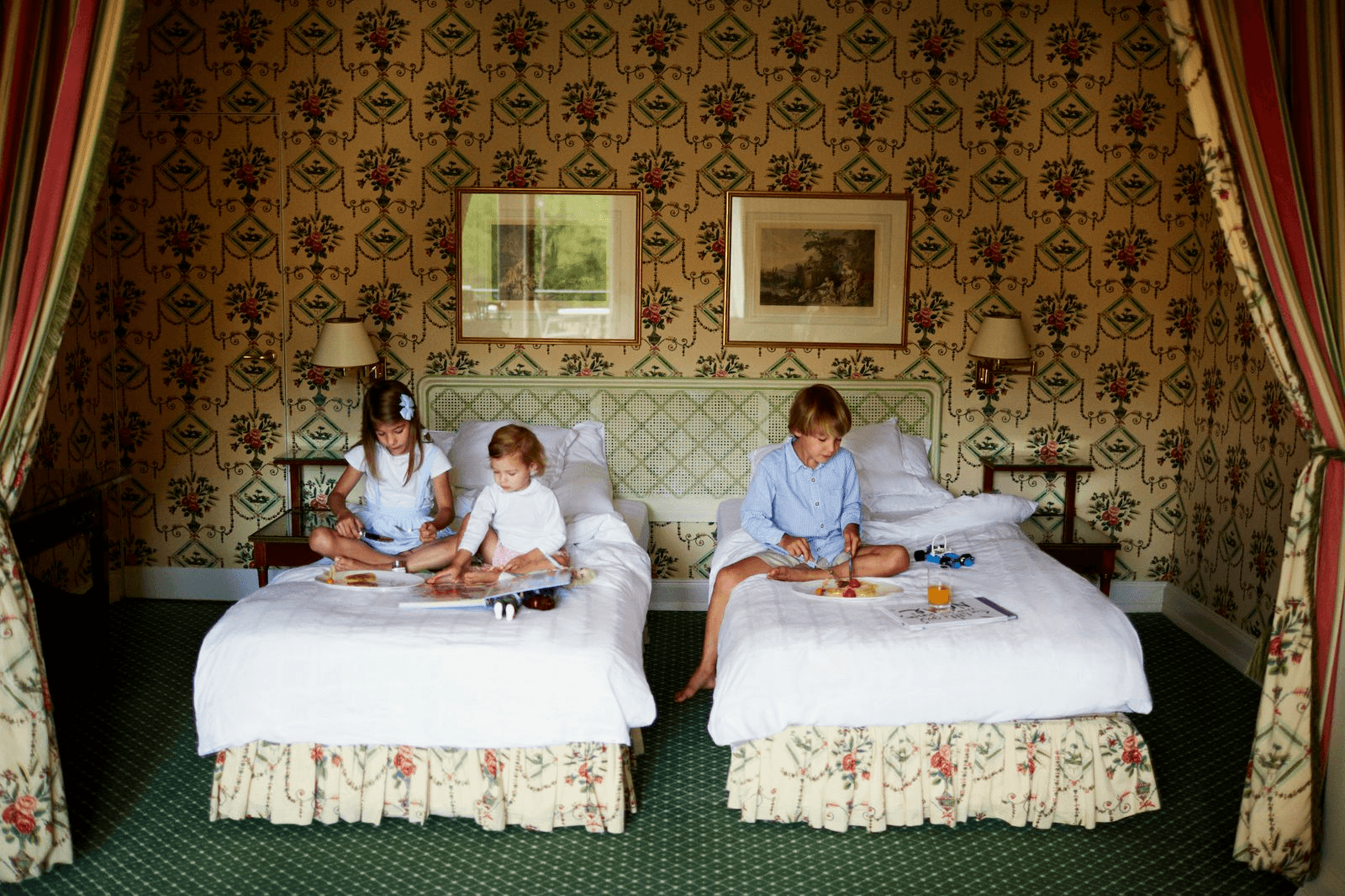 Children playing in a floral-themed room with two beds