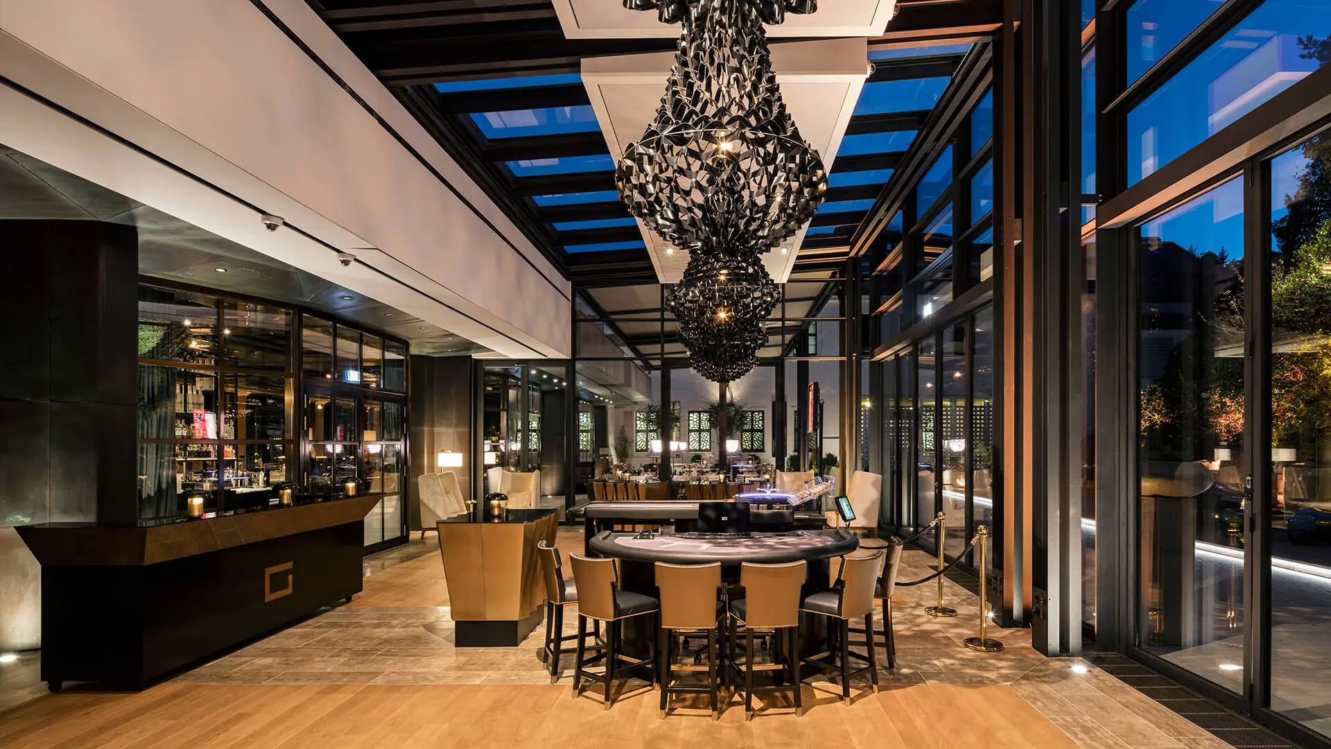Modern restaurant lounge with chandelier, bar, and floor-to-ceiling windows