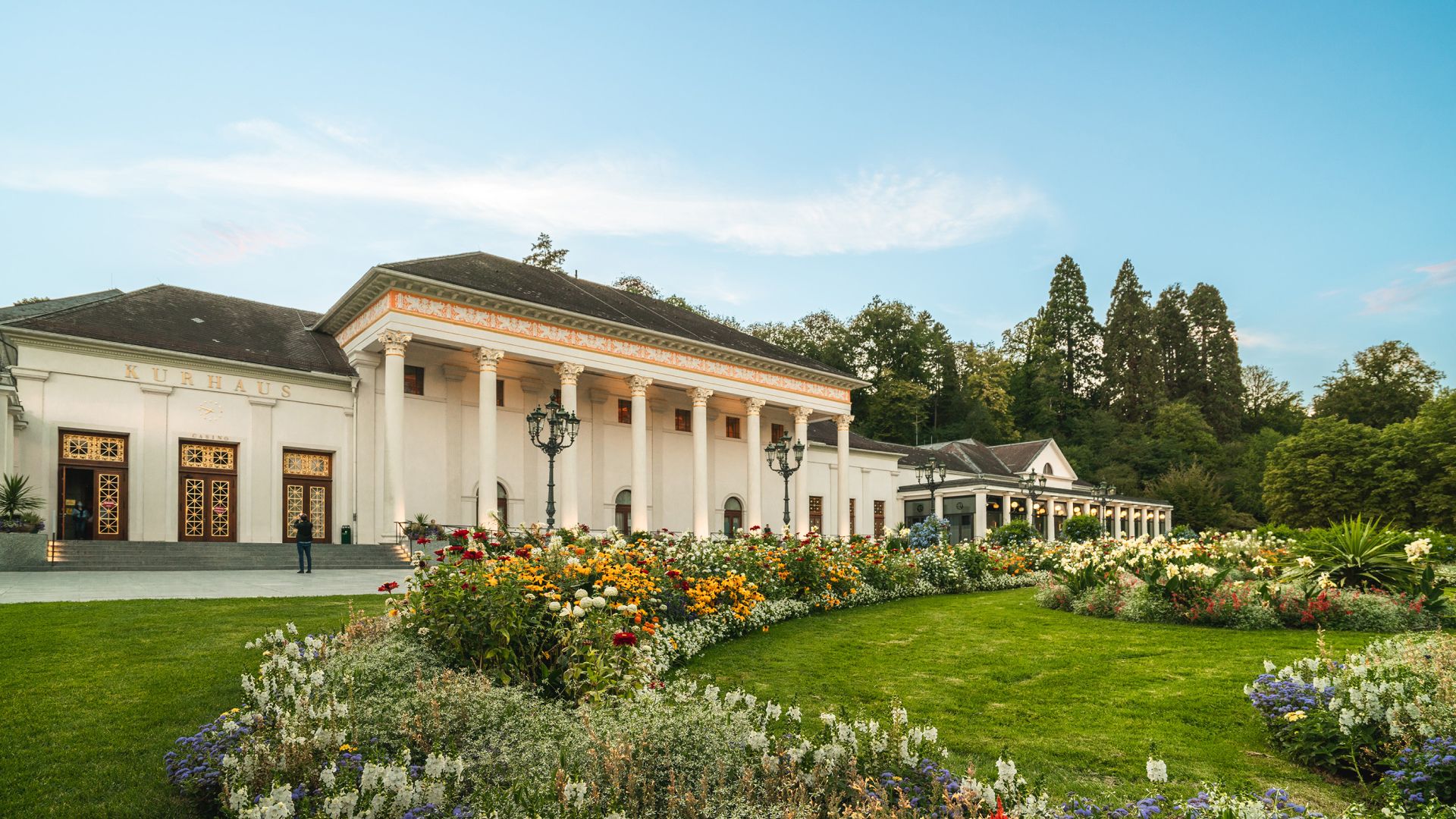 Classical building 'Kurhaus' with columns, garden, and clear sky