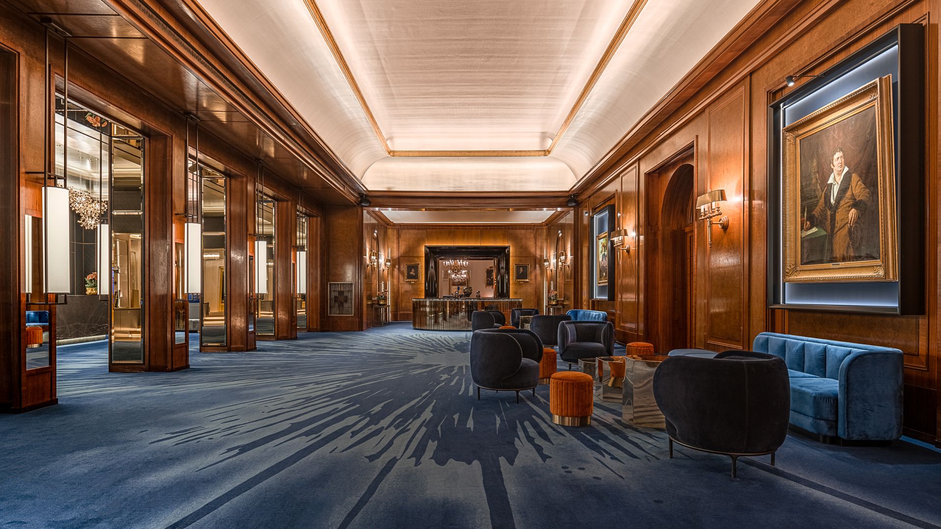 Luxurious hotel lobby with dark wood, blue sofas, and elegant decor.